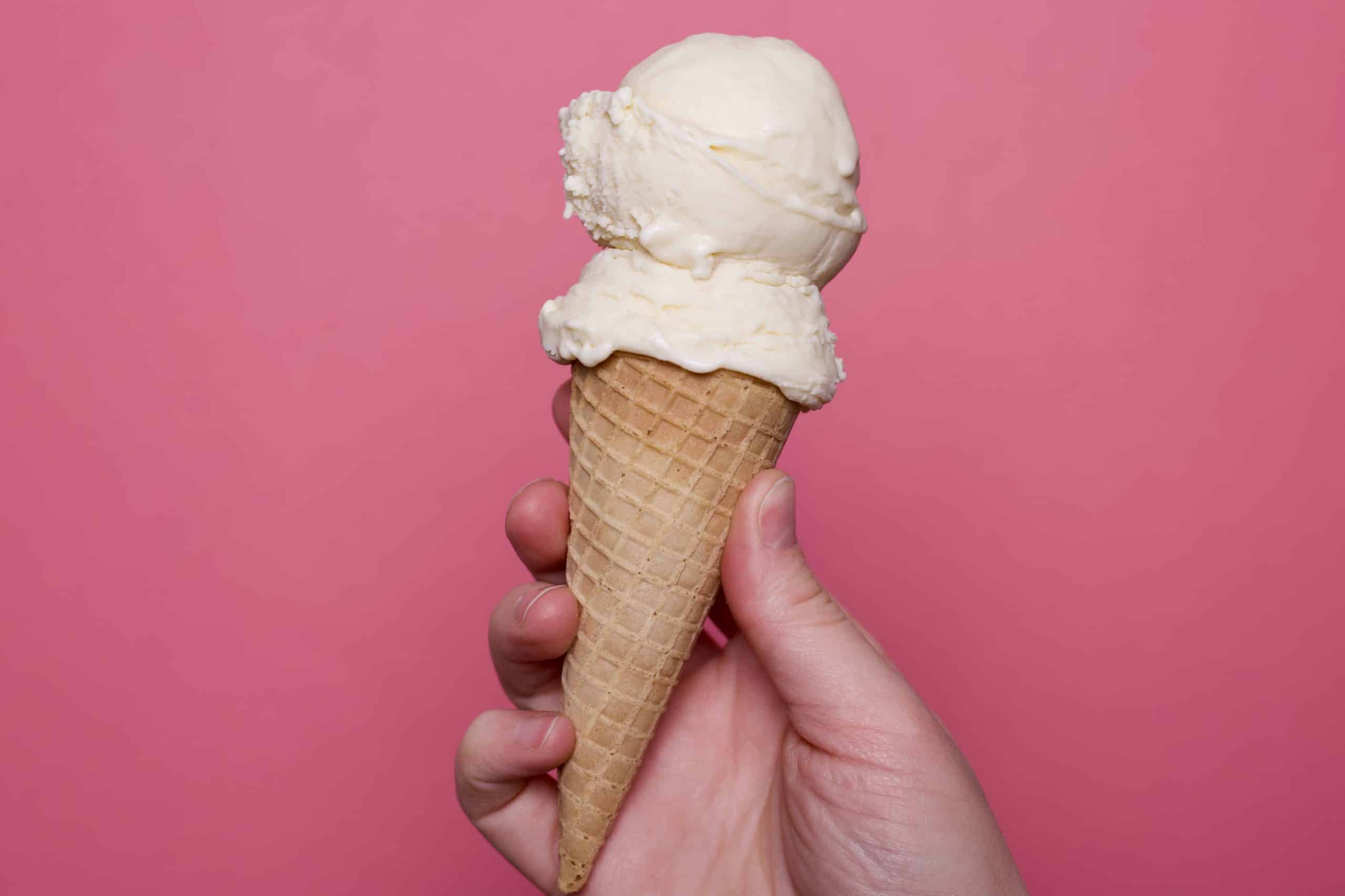 lemon buttermilk ice cream cone against pink background